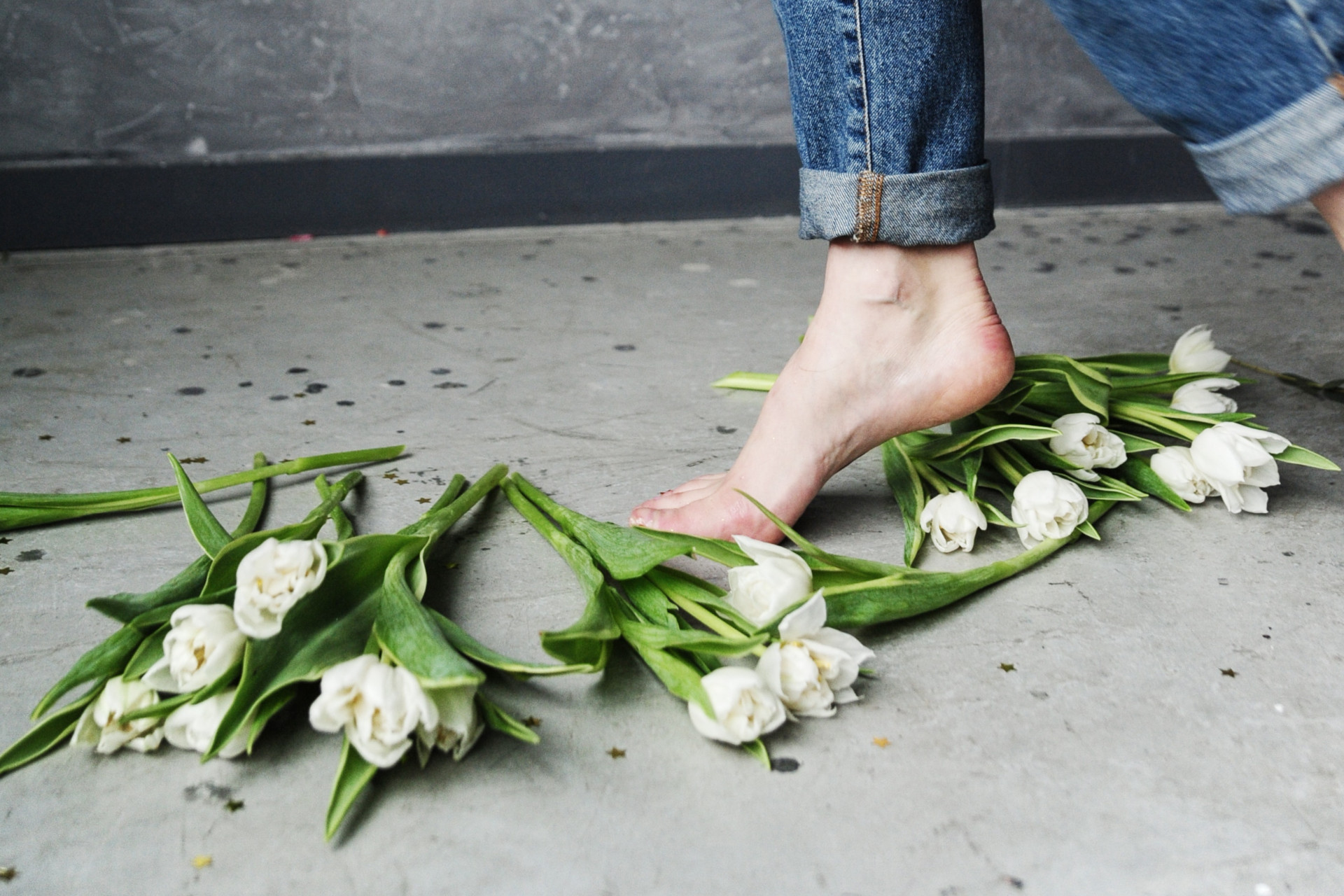kobieta bosymi stopami idzie po białych tulipanach